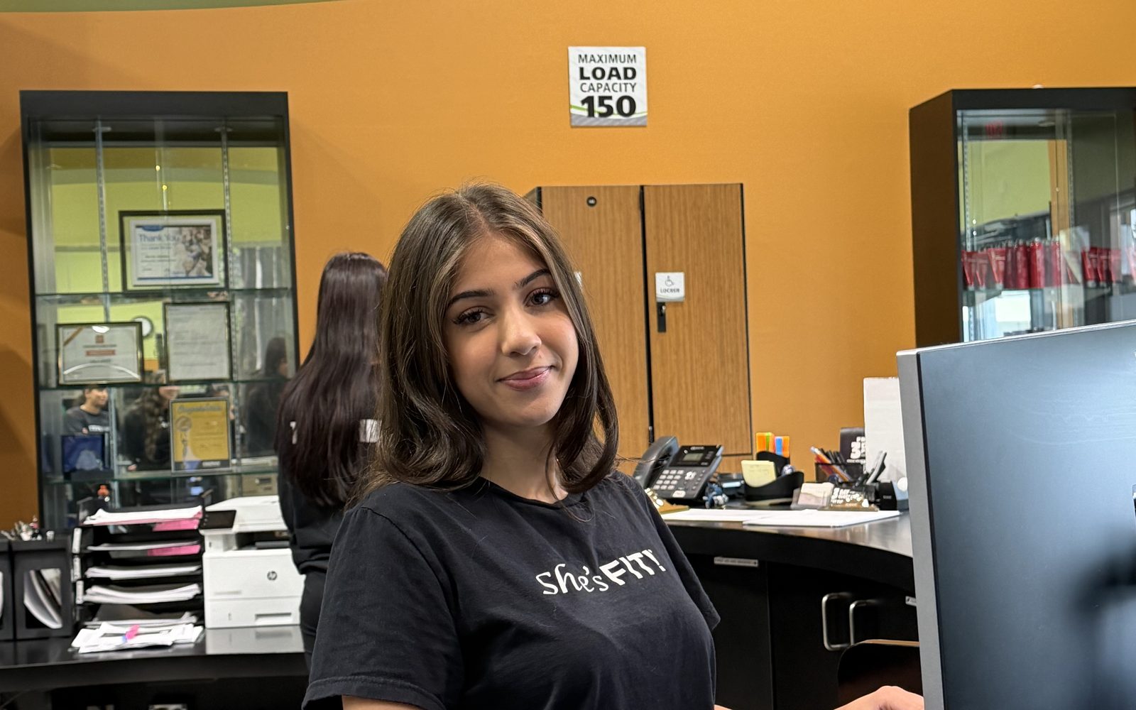A She's FIT! front desk team member at the reception computer