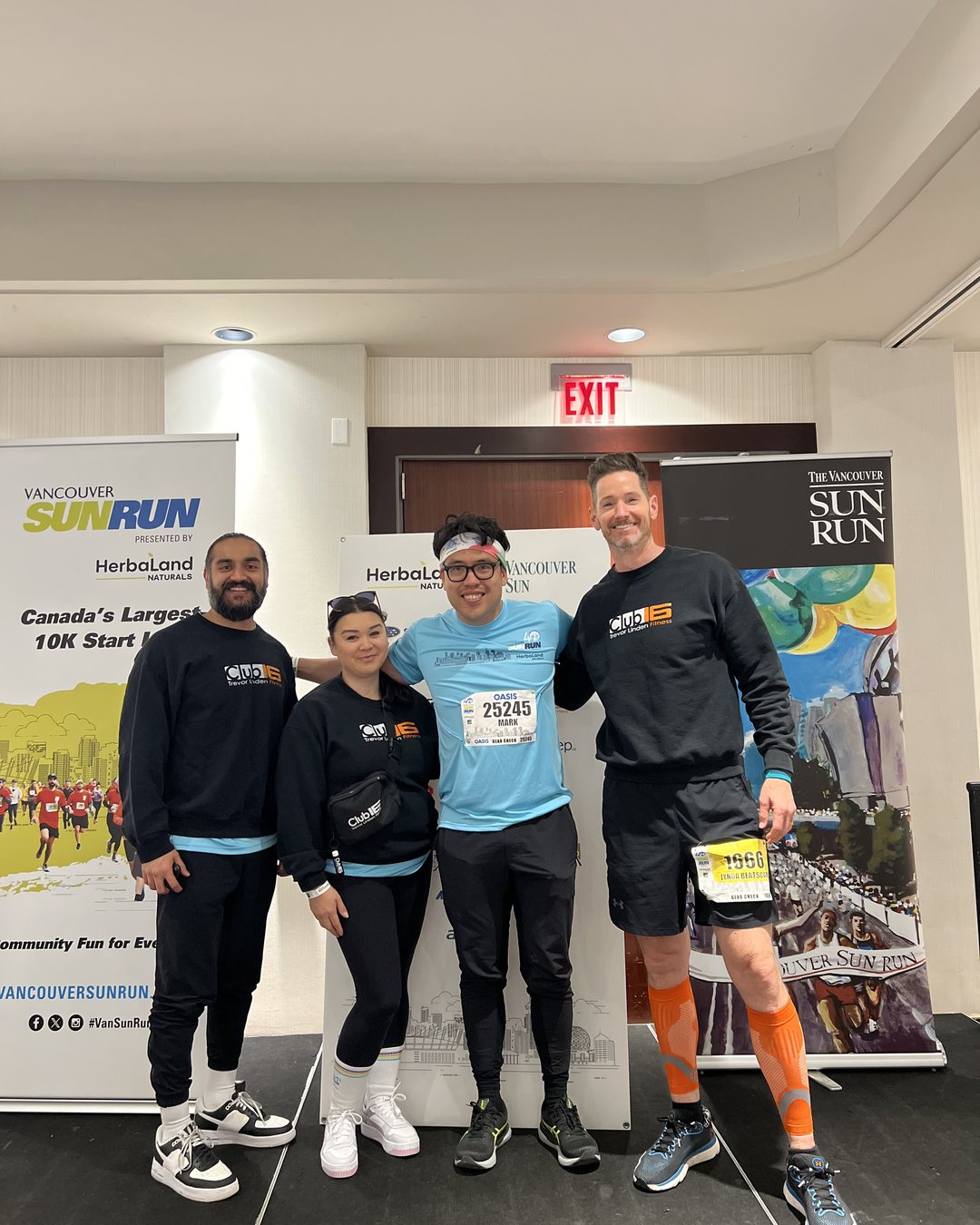 Four Club16 team members in front of the Vancouver Sunrun banner before the race